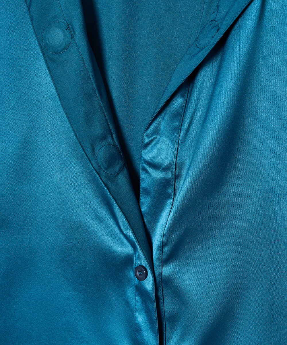 A close-up of a teal blue satin button-down shirt showing the fabric's sheen, collar, and button details.