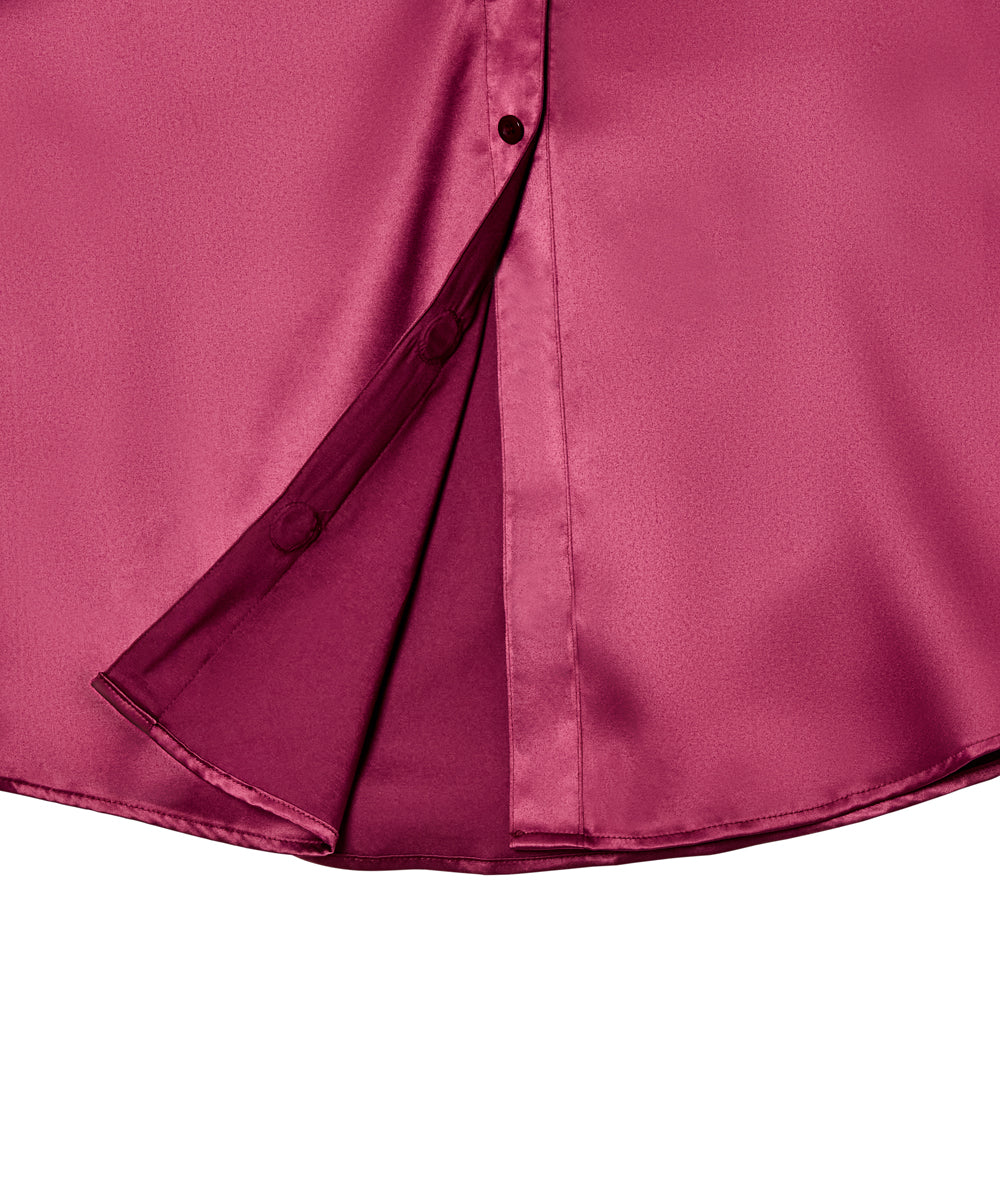 Close-up of a satin-like magenta blouse with a partial button placket and folded front panel, shown against a plain white background.