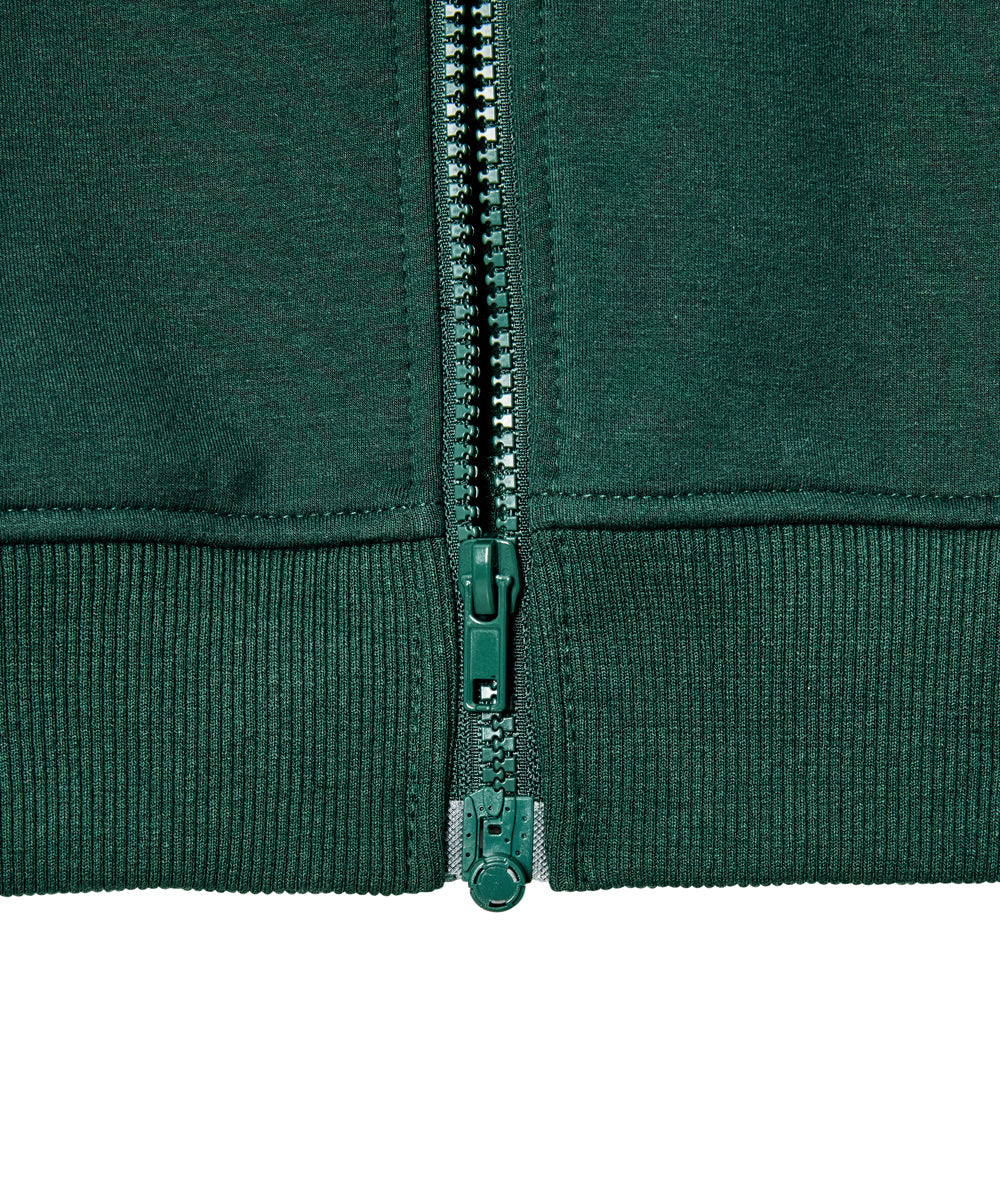 Close-up of a dark green zippered garment with ribbed cuffs and hem, showing the zipper and pull tab in detail against a white background.